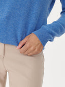 Person wearing a blue sweater and beige pants on a light gray background. #color_blue