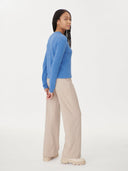 back view of a woman wearing a blue sweater and beige pants on a white background. #color_blue