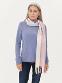 Woman wearing a light purple sweater and a pink and white scarf on a plain background