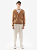 Man wearing a brown cardigan over a white shirt with beige pants on a white background. #color_light-brown