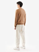 back view of a man wearing a brown sweater and white pants on a white background. #color_light-brown
