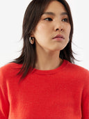 Woman wearing a red sweater against a white background. #color_red-orange