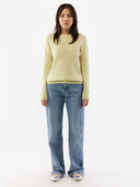 Woman wearing a light green sweater and blue jeans on a white background. #color_cream-yellow