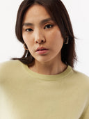 Woman wearing a light green sweater against a white background. #color_cream-yellow
