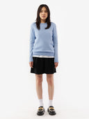 Woman wearing a light blue sweater and black skirt on a white background. #color_muted-blue