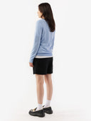 back view of a woman wearing a light blue sweater and black shorts on a white background. #color_muted-blue