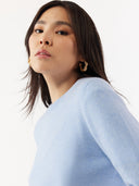 Woman wearing a light blue sweater against a white background. #color_muted-blue