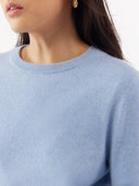 Light blue sweater worn by a person with a neutral background. #color_muted-blue