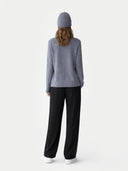 Person wearing a gray sweater and black pants on a white background