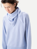 Person wearing a light blue sweater against a white background