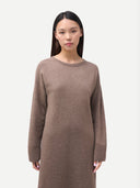 Woman wearing a brown sweater dress against a white background