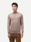 Man wearing a beige sweater and brown pants on a white background