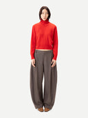 Person wearing a red sweater and gray pants on a white background
