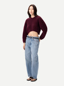 Person wearing a burgundy sweater and light blue jeans on a white background #color_burgundy