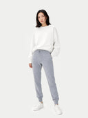 Person wearing a white sweatshirt and gray jogger pants on a white background #color_light-gray