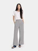 Woman wearing a white top and gray wide-leg pants on a white background. #color_light-gray #ai-image