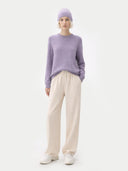 Person wearing a light purple sweater and beige pants on a white background #color_purple-ash
