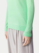 Person wearing a light green sweater and gray pants on a white background. #color_soft-green