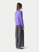 back view of a woman wearing a purple sweater and gray pants on a white background. #color_purple