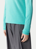 Person wearing a turquoise sweater and gray pants on a white background. #color_aqua-green