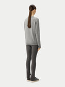 back view of a woman wearing a gray sweater and dark leggings on a white background. #color_urban-silver