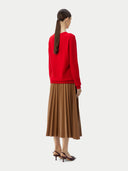 Person wearing a red sweater and brown pleated skirt on a white background. #color_true-red