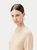 Woman wearing a beige sweater and earrings on a white background. #color_beige