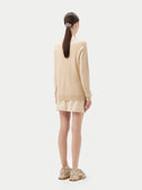 back view of a woman wearing a beige sweater and skirt set on a white background. #color_beige