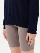 Person wearing a navy sweater and beige shorts on a white background. #color_navy-blue