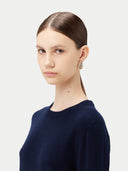Woman wearing a navy blue sweater against a light gray background. #color_navy-blue