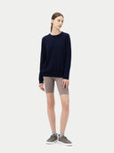 Person wearing a navy sweater and beige shorts on a white background. #color_navy-blue