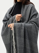 Person wearing a gray striped poncho with tassels on a white background. #color_steel-silver