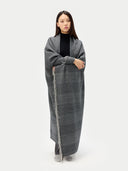 Woman wrapped in a long gray blanket against a white background. #color_steel-silver