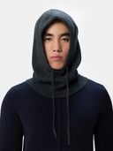 Person wearing a dark gray knitted hoodie against a white background