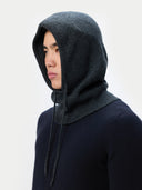 Person wearing a dark gray hooded garment against a light gray background