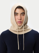 Person wearing a beige hooded garment against a white background