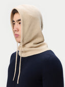 Person wearing a beige knitted hood over a navy sweater on a white background