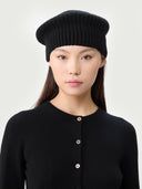 Woman wearing a black knit beret against a white background