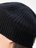 Close-up of a black knit beanie worn by a person with a blurred background