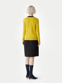 Person wearing a yellow jumper and black skirt on a white background #color_black