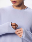 Close-up of a person wearing a pale lavender crewneck sweater, showing the soft knit texture and the cuffs.