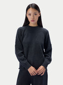 A model wearing a dark charcoal gray knit crewneck sweater and matching dark pants, standing against a light gray studio background.#color_charcoal