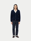 Man wearing a navy cardigan over a white shirt with dark jeans on a white background. #color_navy-blue