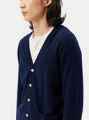 Person wearing a navy blue cardigan over a white shirt on a light gray background. #color_navy-blue