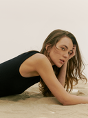 The Nomadic Summer Edit — woman in a black knit cashmere dress lying on sand