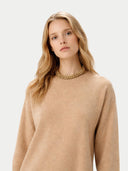 Woman wearing a beige sweater and gold necklace on a white background. #color_beige #ai-image