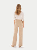 back view of a woman wearing a white blouse and beige pants on a white background. #color_beige #ai-image