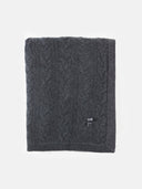 A charcoal gray cable knit cashmere blanket draped over a flat surface.