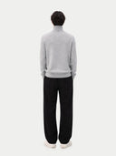 Person wearing a grey jumper and black pants on a white background #color_black