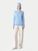 Person wearing a light blue sweater and beige pants on a white background #color_sky-blue
